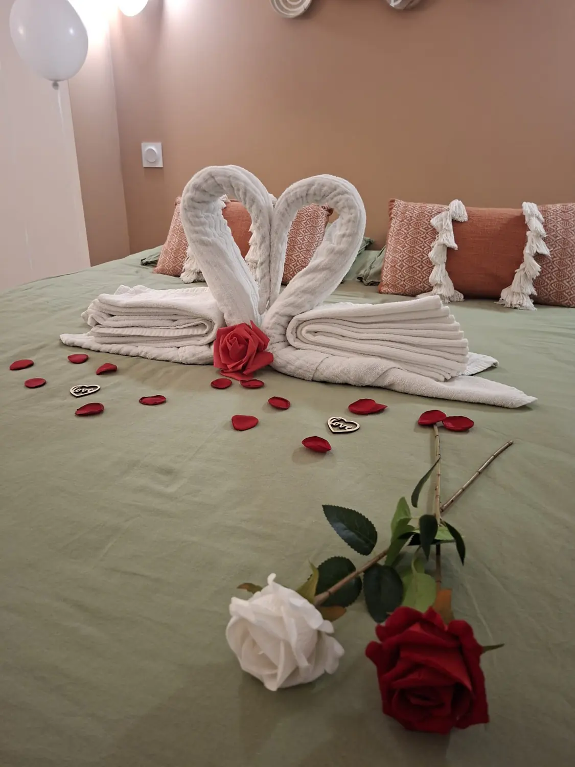 Deux cygnes de serviettes formant un cœur, avec une rose rouge et une rose blanche
