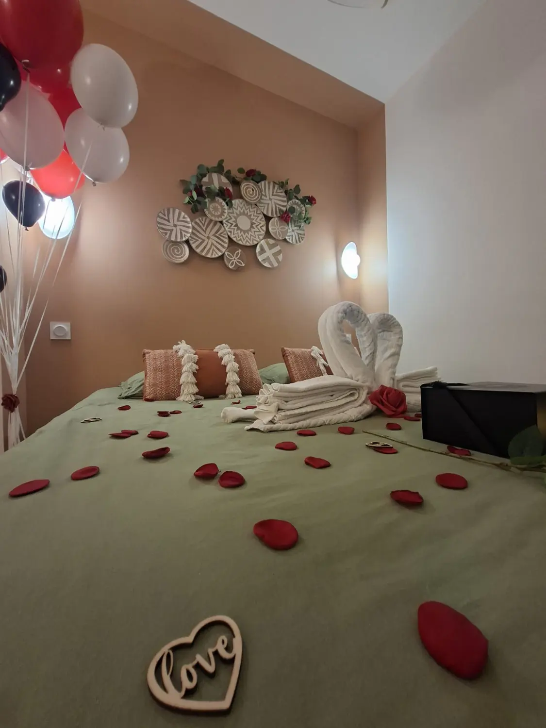 Cygnes de serviettes et roses rouge et blanche posés sur le lit
