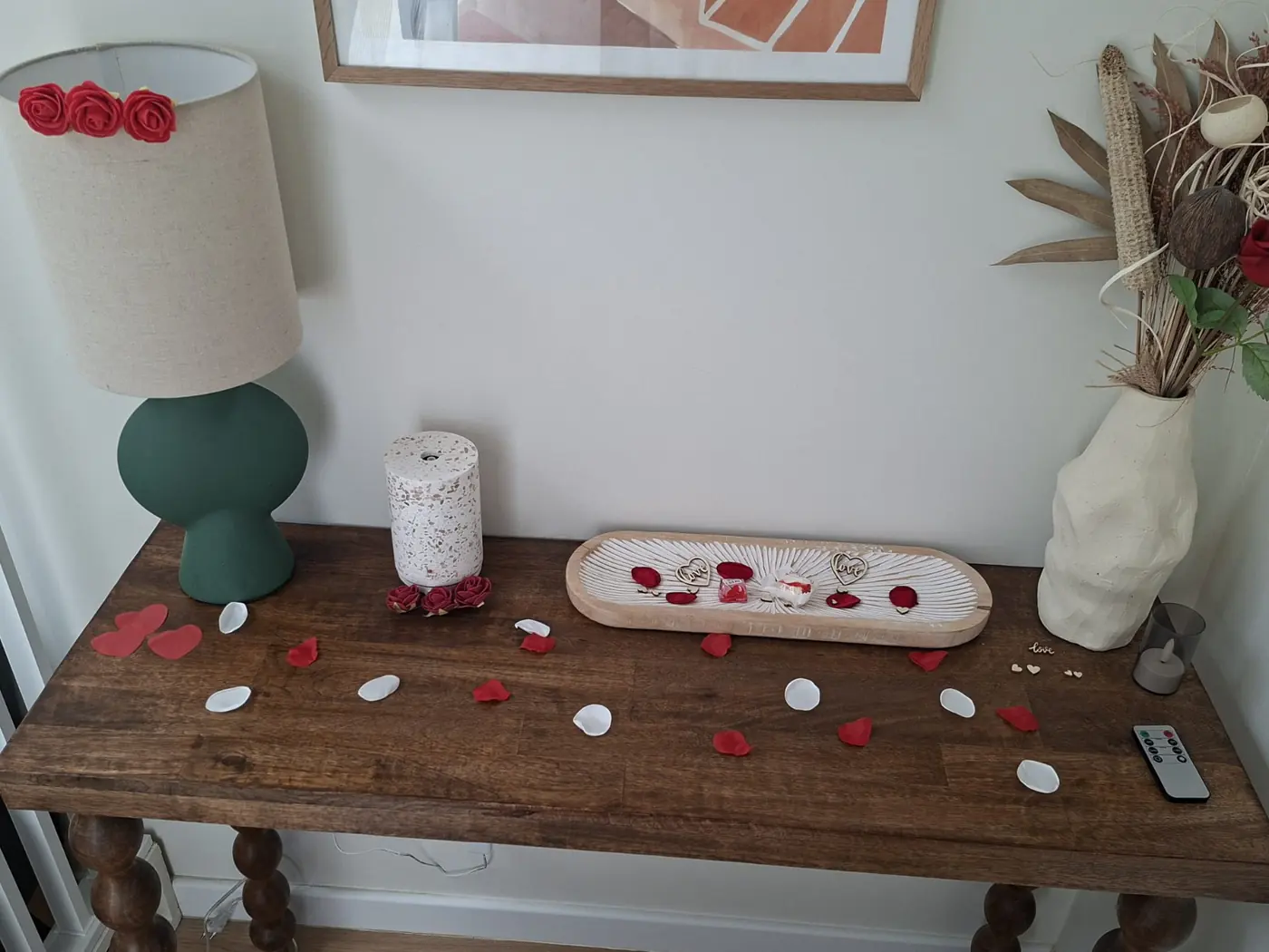 Console décorative avec lampe, fleurs séchées et pétales de roses