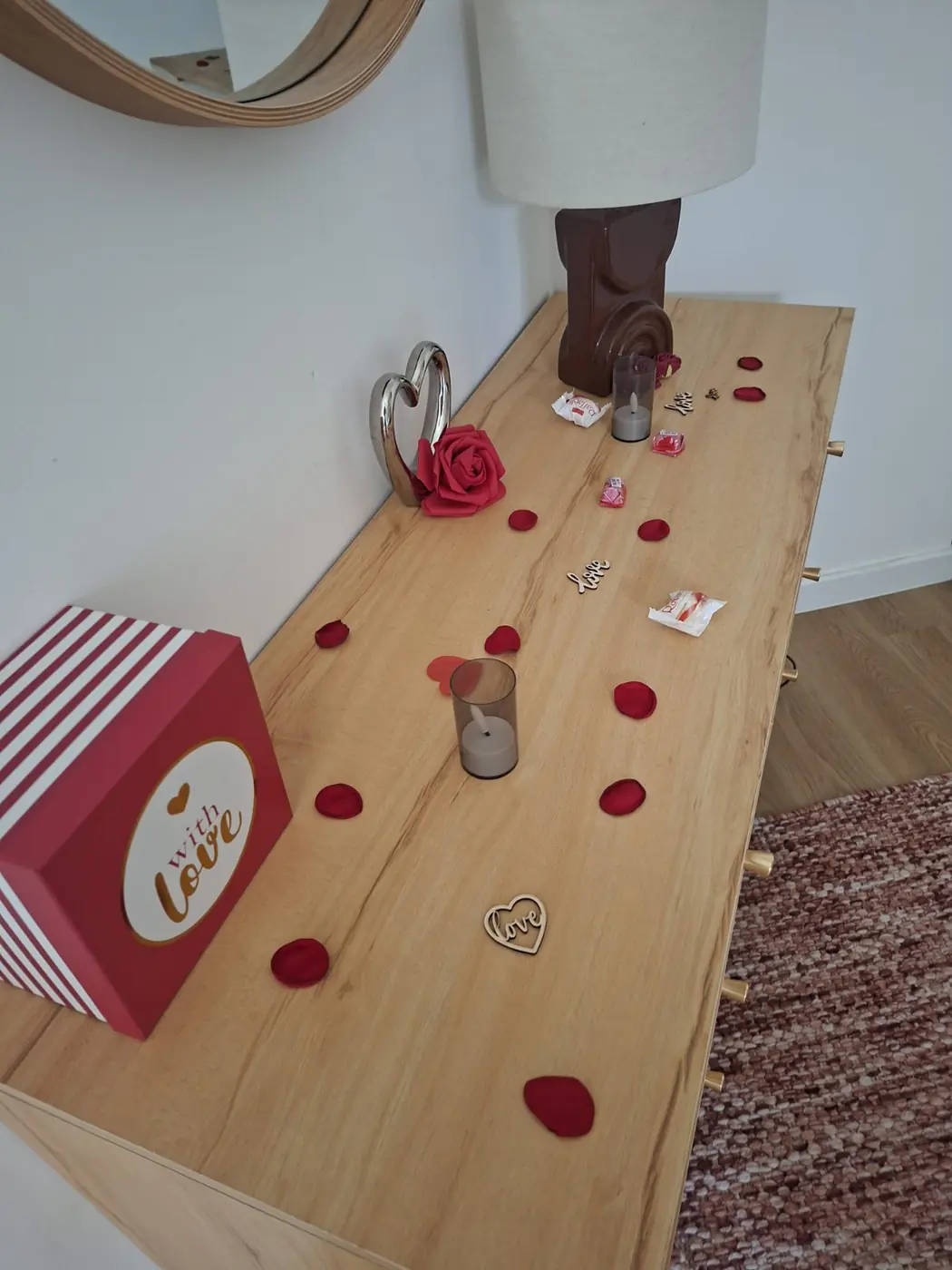 Coffret cadeau, chocolats et pétales disposés sur la console en bois