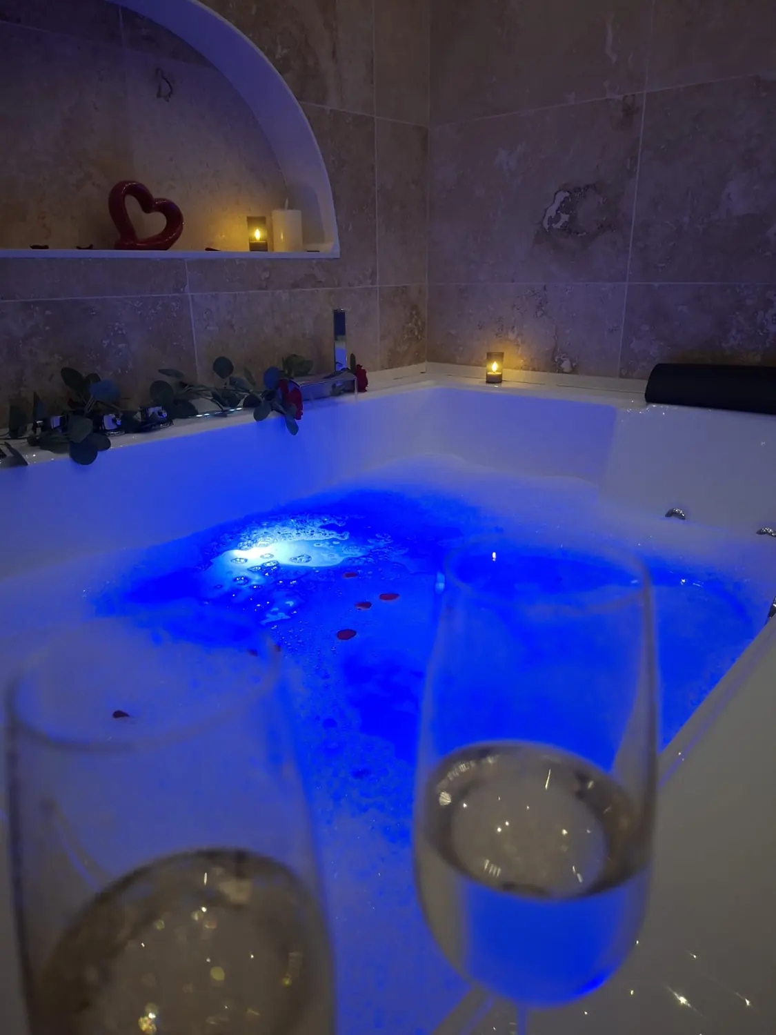 Bain à remous bleuté avec deux coupes de champagne au premier plan